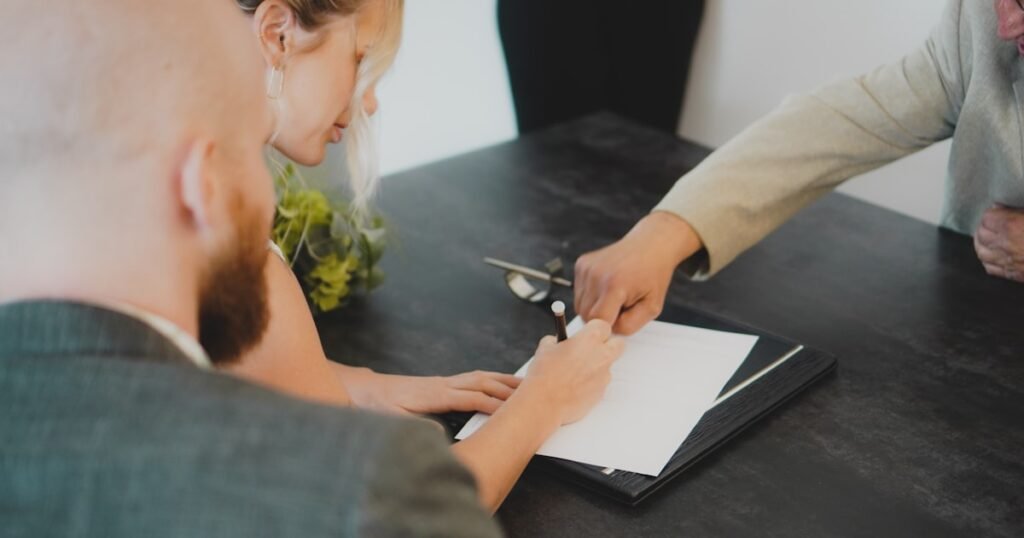 Casal assinando documento sobre a mesa