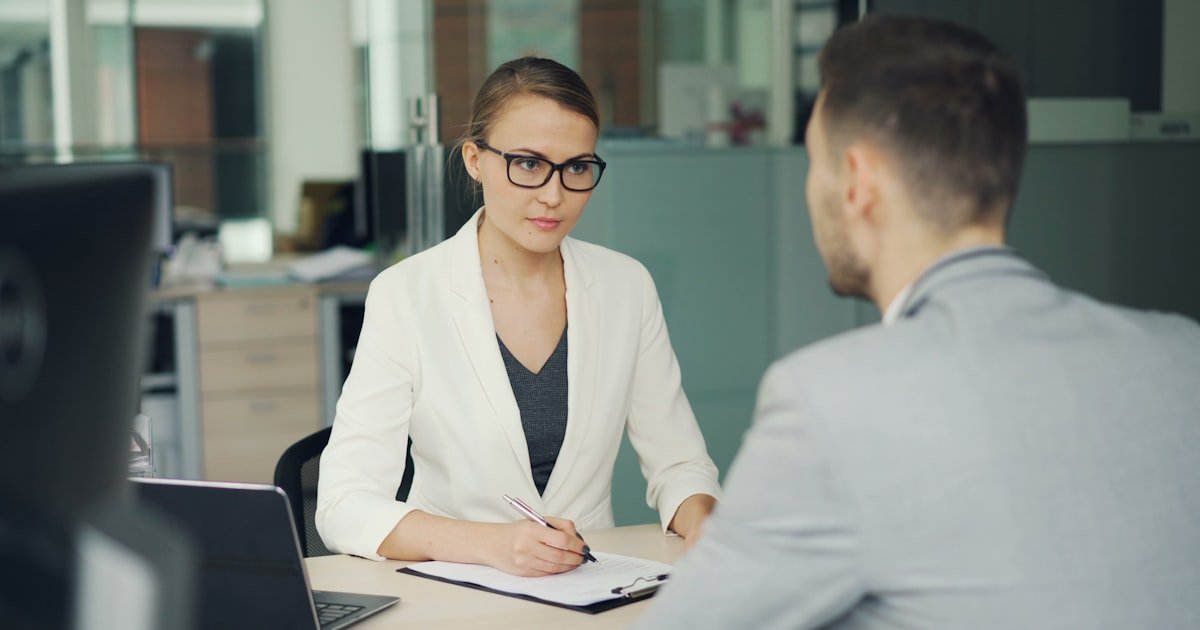 Advogada de óculos orientando cliente na mesa do escritório